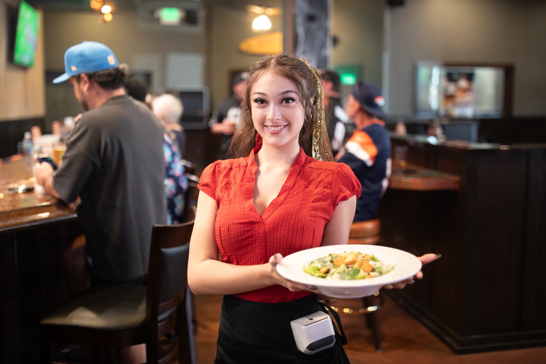 A server bringing a Caesar salad through the bar at Meganos Well