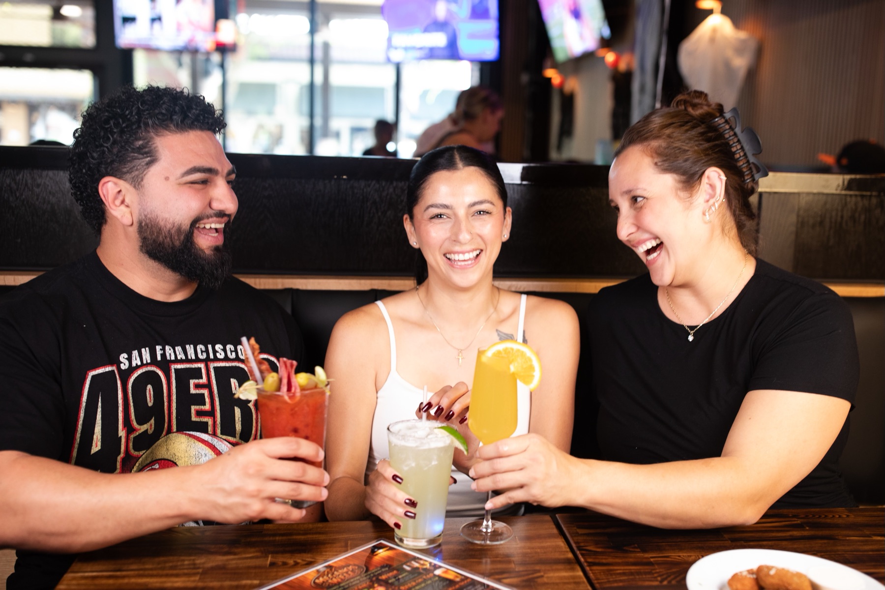 Friends laughing over cocktails at Meganos Well