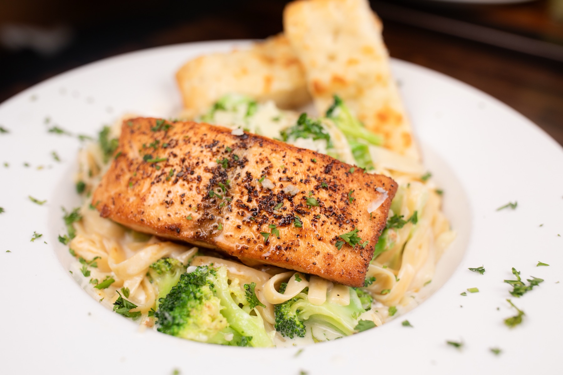Salmon over fettuccine alfredo with garlic bread