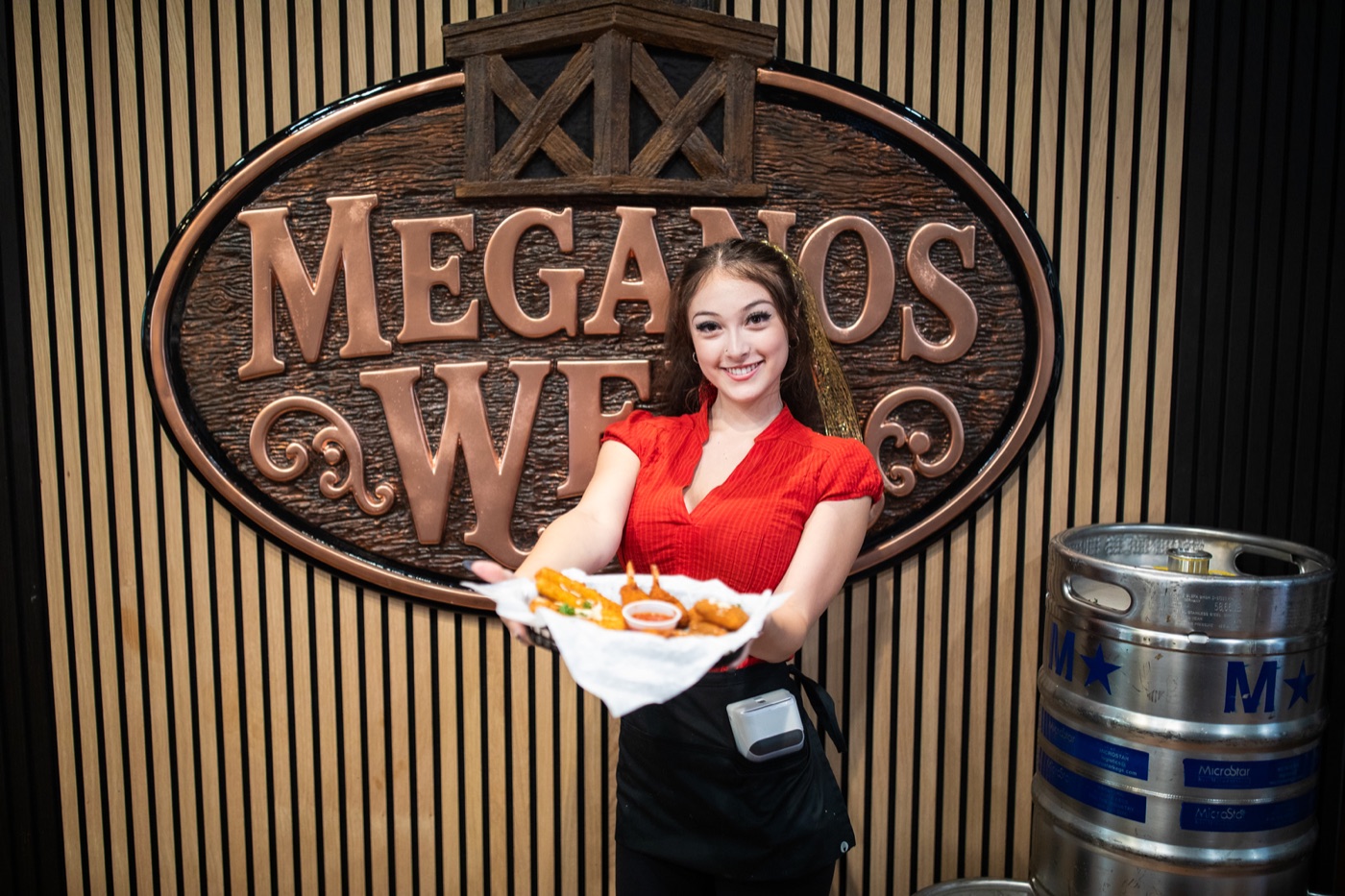 A server holding a plate in front of the carved sign